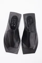 Sandalia tipo chata de cuero vacuno marrón, con diseño de tiras cruzadas y suela plana.