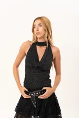 Top sin mangas de tejido lurex negro con acabado brillante, cuello halter y escote cruzado.