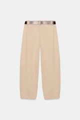 Pantalón tiro bajo color marrón, de corte globo y pernera recta con raya marcada al frente. Incluye trabillas y un cinturón marrón oscuro con hebilla metálica.