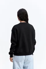 Buzo de algodón color beige con cuello redondo y estampa central rectangular en tonos rosa y dorado. Presenta un diseño de calce relajado con puños y ruedo acanalados.