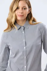 Camisa de manga larga con diseño de rayas verticales, confeccionada en mezcla de algodón, nylon y spandex. Cuenta con cuello camisero clásico y cierre frontal abotonado.