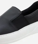 Championes tipo slip-on confeccionadas en cuero napa color negro, con elásticos laterales para un ajuste cómodo y suela robusta de goma en color blanco.