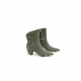 Bota de gamuza verde militar con punta fina, taco ancho y caña corta. Presenta costuras decorativas blancas en forma de cruz en el lateral y una línea horizontal alrededor de la caña. Cuenta con cierre lateral interno.