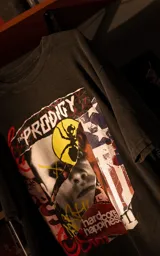 Remera de manga corta con cuello redondo y calce oversize, color negro con efecto nevado. Presenta un estampado gráfico frontal con el logo de la banda The Prodigy y elementos artísticos.
