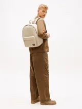 Mochila Tommy Jeans Essential Dome de tejido ripstop en color beige, con diseño curvo, compartimento principal con cierre de cremallera, bolsillo exterior frontal con cremallera, asa superior y correas ajustables y acolchadas. Incluye parche con el logo de la marca en el bolsillo frontal.