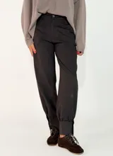 Pantalón de gabardina negro, de corte recto y holgado, con bolsillos delanteros y puños ajustados en los tobillos.