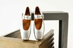 Zapato bajo de gamuza color beige con correa sobre el empeine y hebilla dorada.