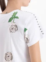 Remera de algodón blanca con estampado de rosas, cuello redondo, mangas cortas y detalle de tachas metálicas en los hombros.