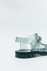 Sandalias estilo romano de PVC transparente en color verde, con suela track dentada y hebilla metálica lateral.