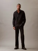 Camisa negra de lino y algodón, de corte clásico, con cuello en punta, cierre frontal con botones y mangas largas con puños abotonados.