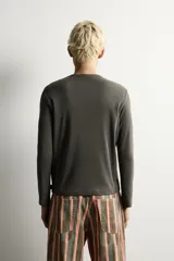 Camiseta de manga larga con cuello redondo, confeccionada en tejido con estructura de canalé y corte relajado.