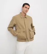 Sobrecamisa de sarga de algodón en color beige, de corte amplio y estructurado, con cuello camisero, mangas largas, cierre frontal de botones ocultos y grandes bolsillos frontales con solapa.