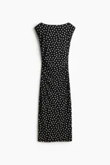 Vestido midi entallado de punto elástico en color negro con estampado de lunares blancos. Presenta escote bote, mangas japonesas y laterales fruncidos que realzan la silueta.