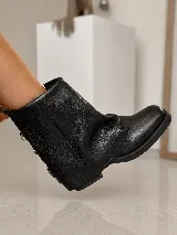 Bota corta de cuero gamuzado color marrón, con diseño de polaina superpuesta y detalle de hebillas metálicas en la parte posterior del talón. Cuenta con suela plana de goma negra y horma amplia.