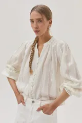 Blusa blanca de algodón con hilos metalizados, cuello mao y escote en V.