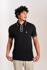 Polo de manga corta confeccionado en tejido interlock suave, color negro con detalles de vivos en color blanco en el cuello y las mangas. Presenta tapeta con botones y un bolsillo frontal con el logo bordado.