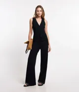 Blusa estilo chaleco, confeccionada en ribana negra, con abotonado delantero, sin mangas y con textura acanalada.