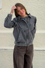 Cazadora de denim en tono gris lavado, con diseño de costuras marcadas, cuello camisero, cierre frontal con botones y bolsillos laterales.
