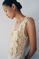 Vestido largo color beige de viscosa, con escote cuadrado, tirantes anchos, detalles drapeados, volantes y aplicaciones de encaje a contraste en el pecho. Cuenta con cierre trasero de botones.