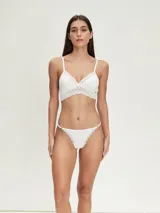 Conjunto de ropa interior blanco, compuesto por un bralette con encaje en el escote y una tanga con detalles de encaje.