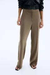 Pantalón de vestir color marrón, tiro alto, con pliegues marcados en la parte delantera y piernas rectas.