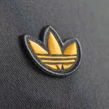 Campera deportiva Adidas del Manchester United, color gris con detalles en dorado. Presenta cierre frontal, cuello alto, bolsillos laterales y escudo del club bordado en el pecho.