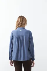 Camisa de manga larga en color celeste, con diseño de corte relajado, cuello clásico y detalle de tablas verticales en el frente.