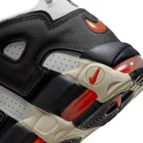 Championes Nike Air More Uptempo 96 de color blanco, negro y gris, con detalles en naranja y rojo. Presentan el característico diseño con las letras "AIR" sobredimensionadas en los laterales, suela de goma con amortiguación visible y un estilo urbano robusto.