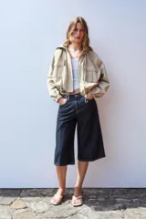 Cazadora color beige con capucha ajustable, manga larga con puño elástico, bolsillos frontales con solapa, bajo ajustable y cierre frontal con cremallera y botones a presión.