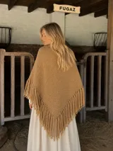 Ruana de lana merino color camel, con diseño triangular, tejido artesanal texturizado y terminación con maxi flecos largos en todo el borde.