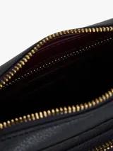 Cartera tipo bandolera Tommy Hilfiger con acabado granulado y diseño integral de monograma TH en relieve. Cuenta con cierre de cremallera, bolsillo exterior frontal con cierre, correa extraíble y apliques metálicos dorados, incluyendo la insignia del monograma TH en el frente.
