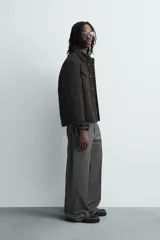 Sobrecamisa de corte relajado confeccionada en tejido efecto piel color marrón oscuro. Presenta cuello solapa, cierre frontal con botones metálicos, mangas largas con puños abotonados y dos bolsillos de plastrón con solapa en el pecho.