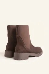 Bota tipo chelsea de gamuza color marrón, con paneles laterales elásticos acanalados y suela de goma track con taco bajo.
