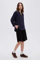 Blusa de viscosa azul marino con cuello mao, escote en V con botones frontales parciales, bolsillo ojal en el pecho y mangas largas con puños abotonados.