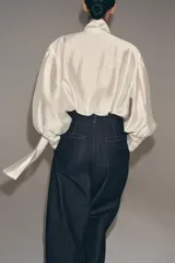 Camisa de corte holgado confeccionada en tejido satinado con mezcla de lyocell. Presenta cuello redondo con escote en pico y lazada frontal integrada. Cuenta con mangas largas abullonadas terminadas en puños anchos y bajo recto.
