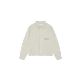 Camisa de manga larga Eme Studios modelo Evo Pirouette, de color beige con diseño de rayas verticales finas. Presenta un bolsillo aplicado en el pecho con el logotipo de la marca bordado en verde oscuro, cuello camisero y cierre frontal de botones.