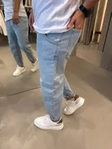 Jean de corte slouchy en color celeste claro, con diseño de tiro medio y ajuste holgado en las piernas que se estrecha hacia los tobillos.