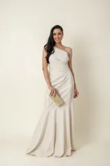 Vestido largo de fiesta color marfil/champagne, confeccionado en lurex. Diseño drapeado con un solo hombro.