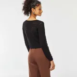 Chaqueta corta de croché color negro, con escote redondo y lazos frontales para atar.