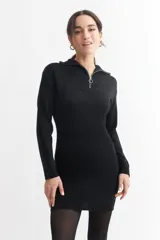Vestido corto de tejido de punto acanalado en color negro, con cuello polo y cierre frontal parcial. Presenta mangas largas y un ajuste entallado al cuerpo.