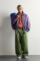 Cazadora regular fit de algodón color violeta con efecto lavado, cuello solapa y cierre de cremallera de doble dirección. Posee bordado frontal de gráficos Fruit of the Loom, bolsillos de vivo en la cadera y acabados con elástico.