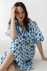 Vestido midi de lino con estampado floral azul y blanco, cuello clásico, mangas abullonadas hasta el codo y cierre frontal con botones de nácar.