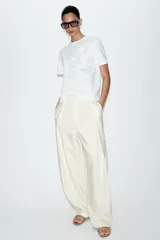 Camiseta blanca de algodón con cuello redondo y manga corta, destacada por aplicación de flores tridimensionales a tono en el frente.