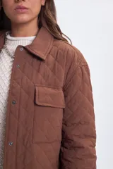 Sobrecamisa de diseño capitoneado en color marrón, con cuello clásico, cierre frontal mediante botones a presión y bolsillos frontales con solapa.