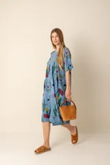 Vestido largo azul claro con estampado abstracto de caras y formas en colores rojo, amarillo, verde y negro. Tiene cuello redondo y mangas cortas.