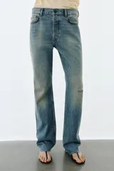 Jeans de tiro medio con corte slim y largo completo. Presentan diseño de cinco bolsillos, cierre frontal con cremallera y botón, efecto lavado y detalle de rotura en la parte delantera con bajo sin costura.