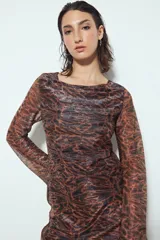 Vestido corto de manga larga, escote redondo y calce ajustado. Confeccionado en tejido liviano con estampado tipo damasco o paisley en tonos negro, marrón y dorado/plateado brillante.