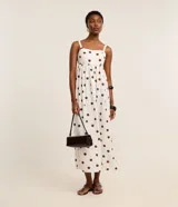 Vestido midi evasé sin mangas, confeccionado en tejido airflow color blanco con estampado de lunares marrones. Presenta escote corazón, breteles anchos con elásticos y lastex en la espalda.