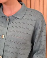 Cardigan de punto a rayas horizontales en tonos beige y tostado, con cuello camisero, cierre frontal de botones y mangas largas.