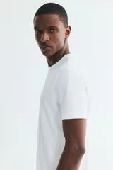 Remera blanca de manga corta de H&M, corte slim fit con cuello redondo ribeteado y bajo recto. Confeccionada con fibra COOLMAX, ligera y transpirable.
